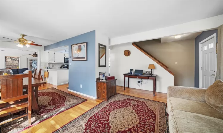 Living room featuring baseboards, light wood-type flooring, and ceiling fan