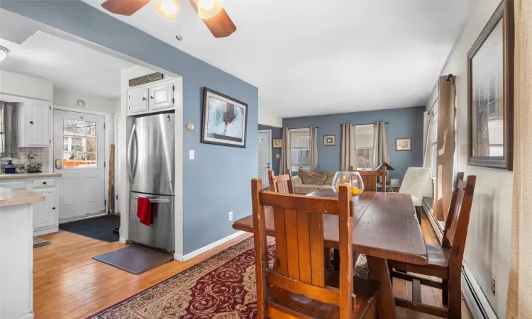 Dining space with light wood finished floors, ceiling fan, baseboards, and a baseboard radiator