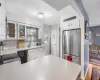 Kitchen featuring backsplash, black dishwasher, light wood-style flooring, freestanding refrigerator, and a sink