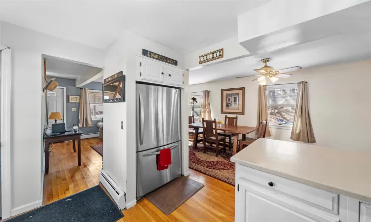 Kitchen with white cabinetry, freestanding refrigerator, a baseboard heating unit, light wood-type flooring, and baseboard heating