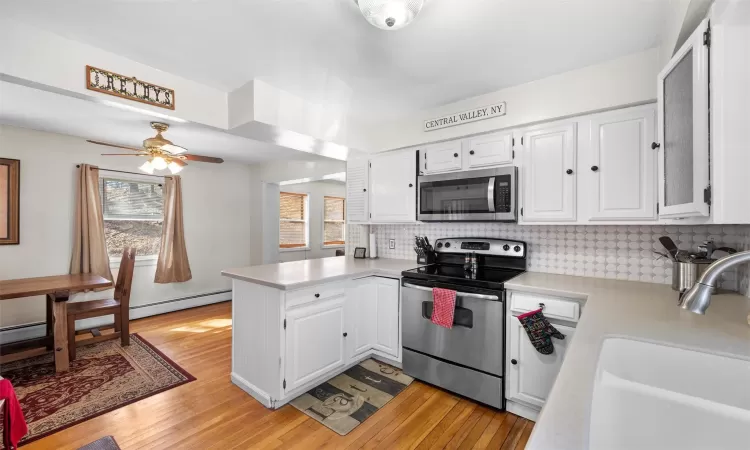 Kitchen featuring a peninsula, a sink, light countertops, white cabinets, and appliances with stainless steel finishes