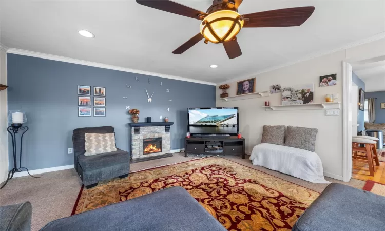 Carpeted living area featuring recessed lighting, a fireplace, baseboards, and ornamental molding