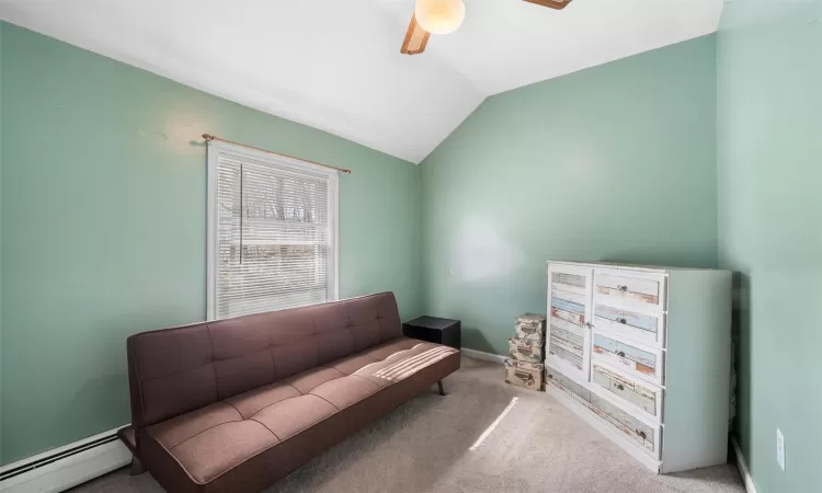 Living area with carpet, baseboards, a ceiling fan, vaulted ceiling, and a baseboard heating unit