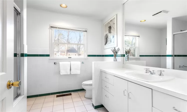 Full bathroom featuring vanity, an enclosed shower, tile patterned floors, toilet, and tile walls