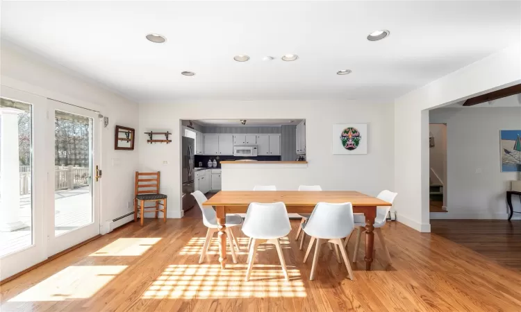 Dining area with light wood finished floors, crown molding, baseboards, baseboard heating, and recessed lighting