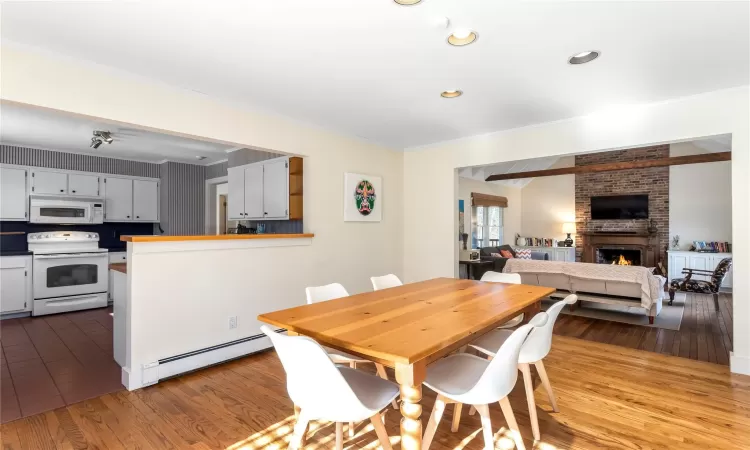 Dining area with recessed lighting, a fireplace, ornamental molding, hardwood / wood-style flooring, and a baseboard heating unit