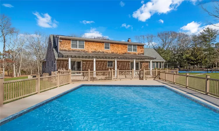 Rear view of property featuring a yard, a fenced in pool, roof with shingles, and a chimney