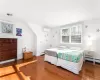 Bedroom with baseboard heating, a wall mounted AC, visible vents, and wood finished floors