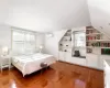 Bedroom with vaulted ceiling, light wood-style flooring, and a wall mounted AC