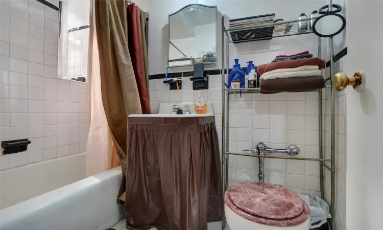 Bathroom featuring tile walls and shower / bath combo with shower curtain