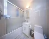 Bathroom featuring vanity, toilet, and bath / shower combo with glass door