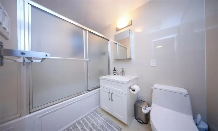 Bathroom featuring vanity, toilet, and bath / shower combo with glass door