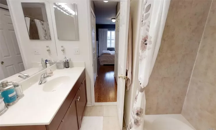 Bathroom featuring curtained shower, a bathing tub, vanity, and tile patterned flooring