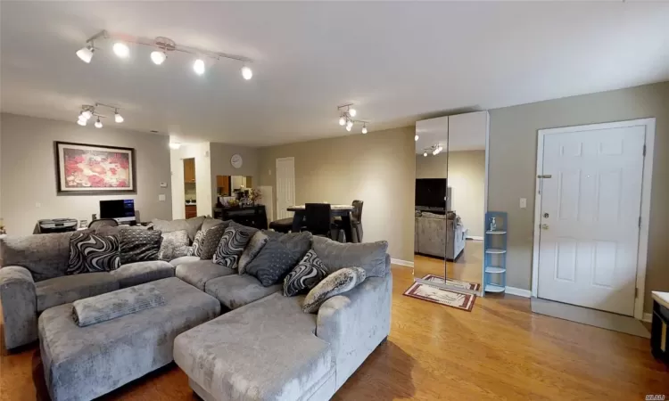 Living area with track lighting, light wood-style flooring, and baseboards