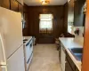 Kitchen featuring under cabinet range hood, a sink, white appliances, wood walls, and light countertops