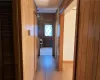 Hallway with light wood-type flooring and wood walls