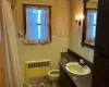 Bathroom with a wainscoted wall, a healthy amount of sunlight, radiator heating unit, and wallpapered walls