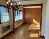 Unfurnished dining area featuring hardwood / wood-style flooring, a notable chandelier, radiator, and baseboards