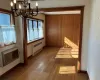 Unfurnished dining area with hardwood / wood-style flooring, a notable chandelier, radiator heating unit, and baseboards