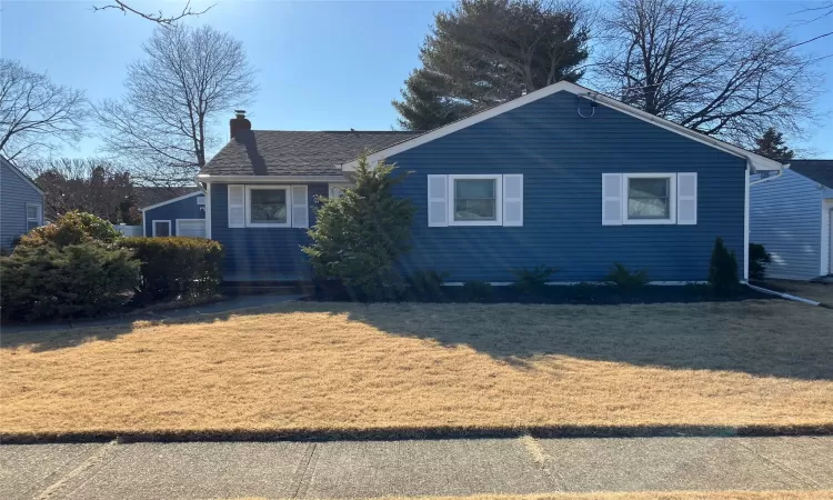 View of front of home with a front lawn, roof with shingles, and a chimney