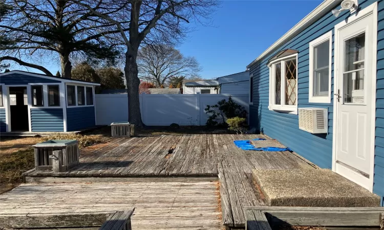 Deck with an outbuilding, central air condition unit, and fence