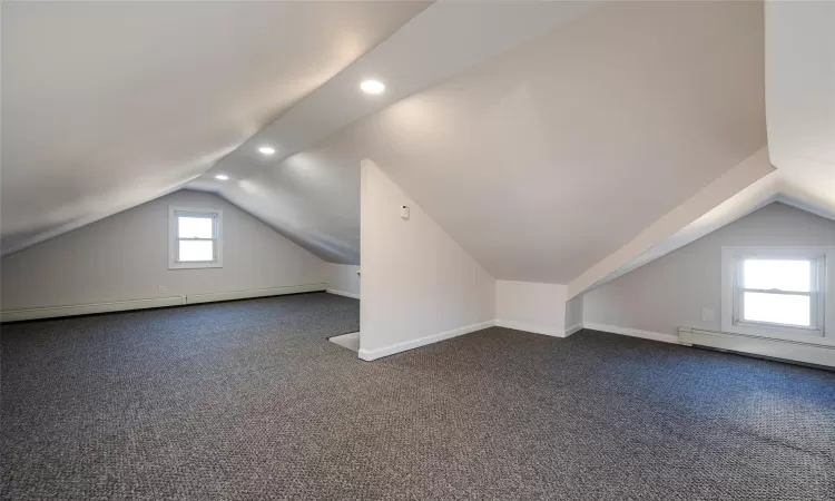 Bonus room featuring vaulted ceiling, baseboard heating, baseboards, and dark colored carpet