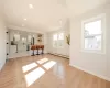 Living area with crown molding, light wood-style floors, baseboards, and baseboard heating