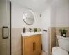 Bathroom featuring visible vents, toilet, tile walls, and vanity