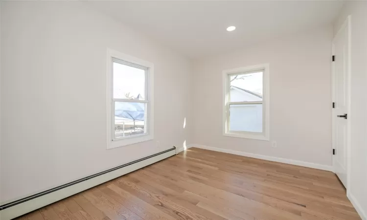 Spare room featuring light wood finished floors, baseboard heating, recessed lighting, and baseboards