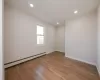 Spare room featuring recessed lighting, light wood-style flooring, baseboards, and a baseboard radiator