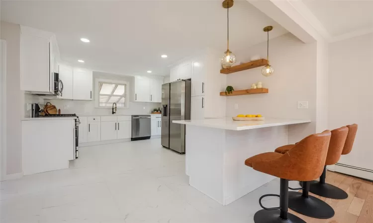 Kitchen with marble finish floor, a sink, stainless steel appliances, a peninsula, and crown molding