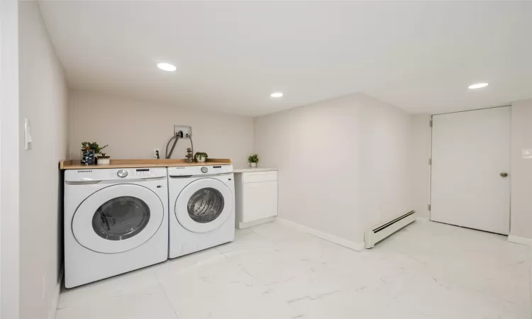 Laundry room with recessed lighting, marble finish floor, washing machine and dryer, and a baseboard heating unit