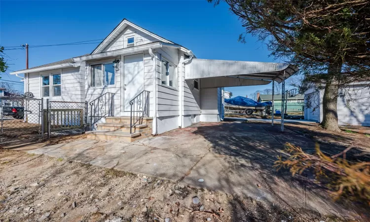 View of front of house with a gate, driveway, a carport, and fence