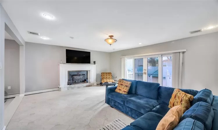 Living room featuring visible vents, a fireplace, french doors, and a baseboard radiator