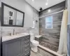 Full bath featuring a tile shower, toilet, vanity, and tile walls