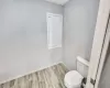 Bathroom featuring toilet, baseboards, and wood finished floors