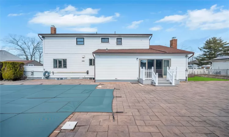 Back of house with a patio area, fence, and a chimney