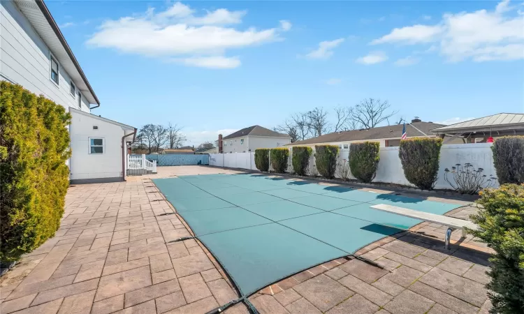 View of pool featuring a fenced backyard, a fenced in pool, a patio, and a diving board