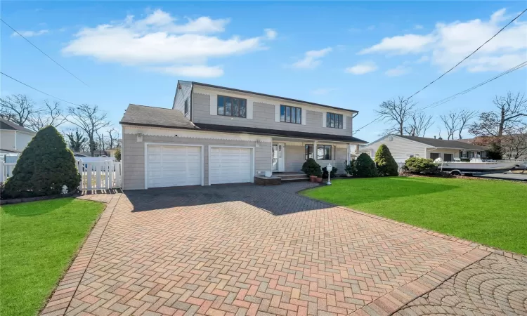 View of front of property featuring a front yard, fence, a porch, a garage, and decorative driveway