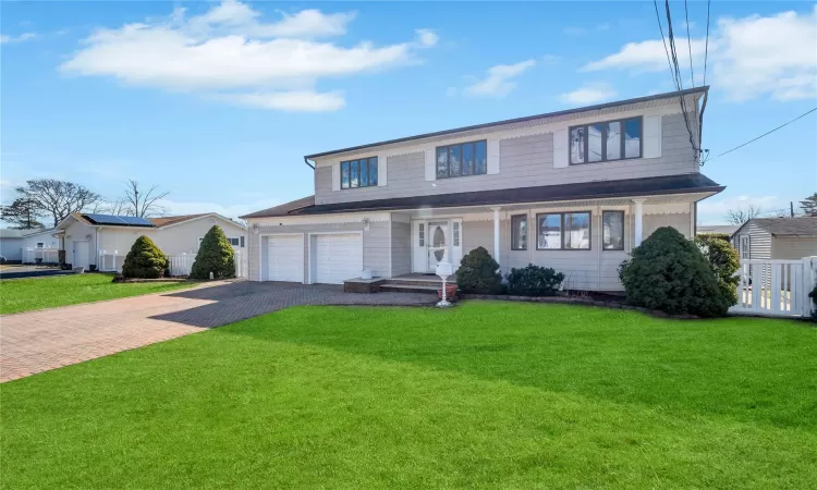 View of front of home with decorative driveway and a front lawn