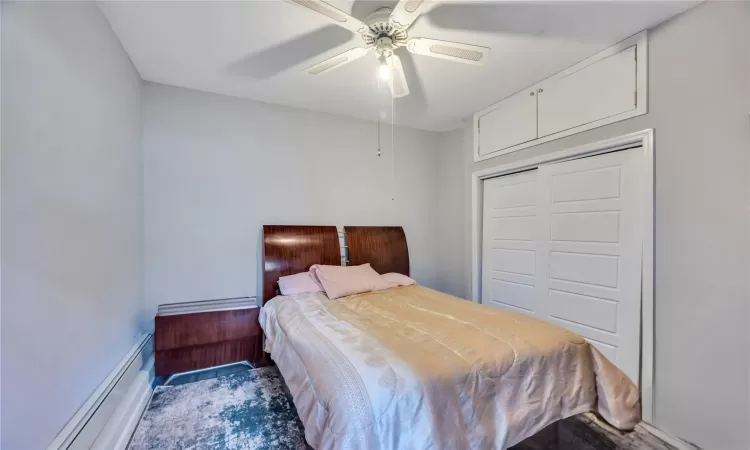 Bedroom featuring a baseboard heating unit, a closet, and a ceiling fan