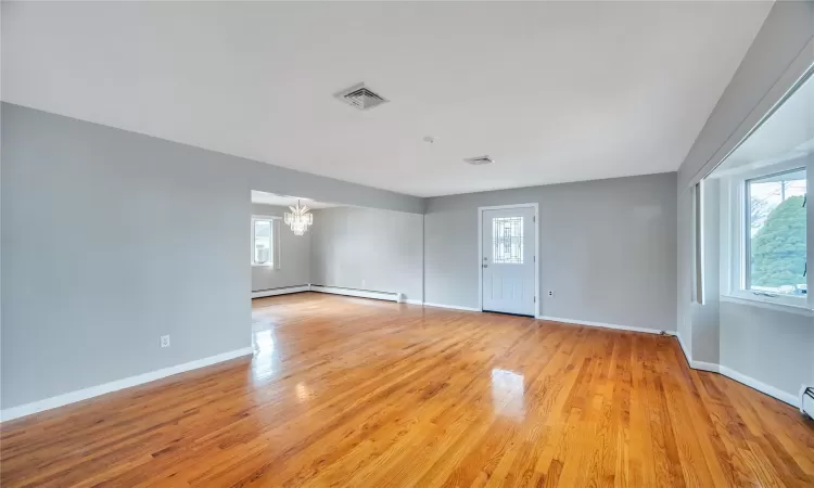 Empty room with visible vents, baseboards, light wood-style floors, and an inviting chandelier