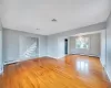 Unfurnished room with visible vents, a baseboard heating unit, stairs, and light wood-type flooring