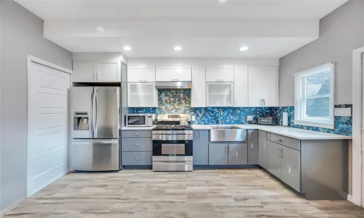 Kitchen with white cabinets, tasteful backsplash, appliances with stainless steel finishes, and a sink