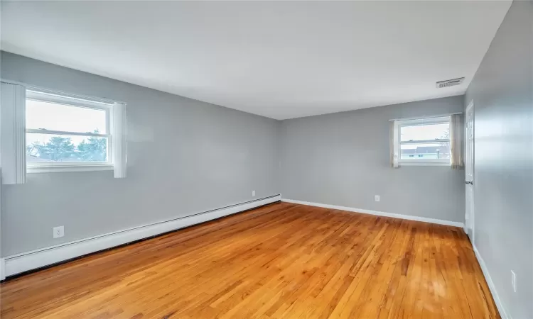 Spare room featuring baseboards, visible vents, baseboard heating, and light wood-type flooring