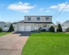 Traditional-style home with an attached garage, decorative driveway, a front yard, and fence