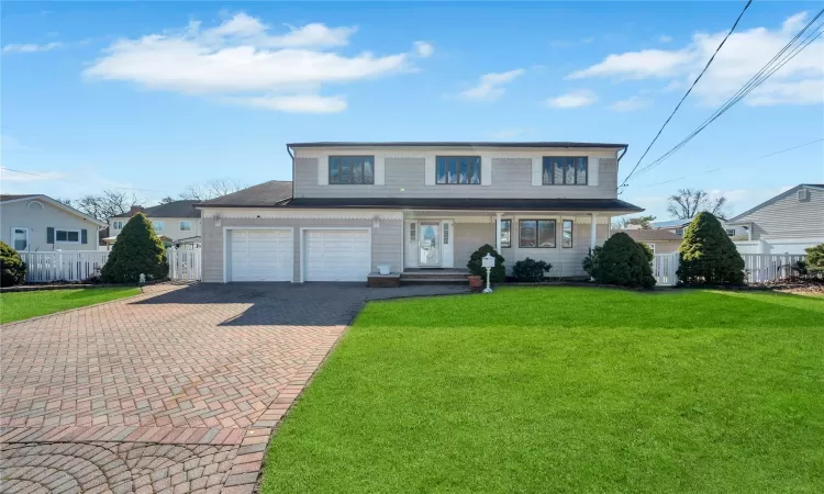 Traditional-style home with an attached garage, decorative driveway, a front yard, and fence