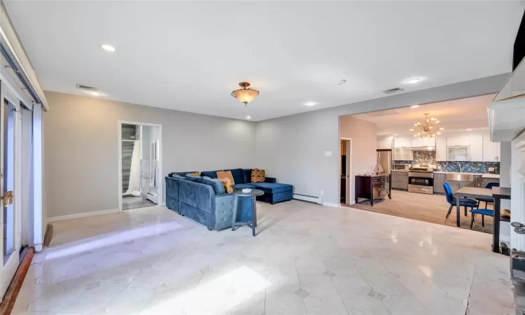 Living area with baseboards, visible vents, baseboard heating, and a chandelier