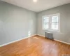 Empty room with light wood-style flooring, radiator heating unit, and baseboards