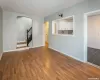 Unfurnished living room featuring stairway, wood finished floors, arched walkways, and baseboards